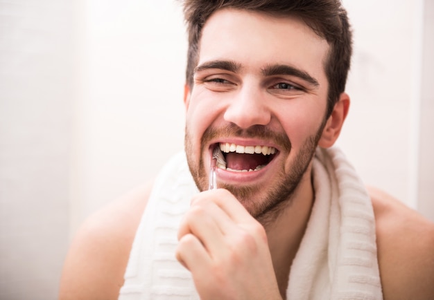 Homme se brosser les dents et se regarder dans le miroir.