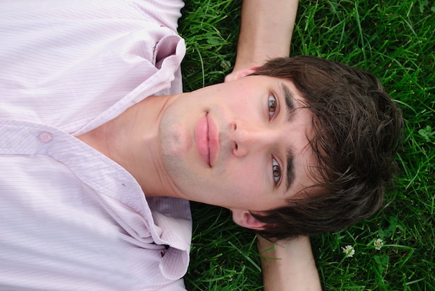 L'homme se couche sur l'herbe et regarde vers le haut. Shallow DOF. Portrait extérieur