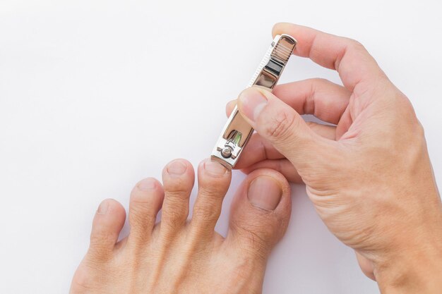 L'homme se coupe les ongles des pieds avec une pince à épiler sur fond blanc Illustration du soin des ongles Pour leur bonne hygiène