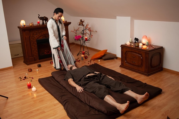 Un homme se fait masser par une femme dans une pièce avec des bougies et des bougies.