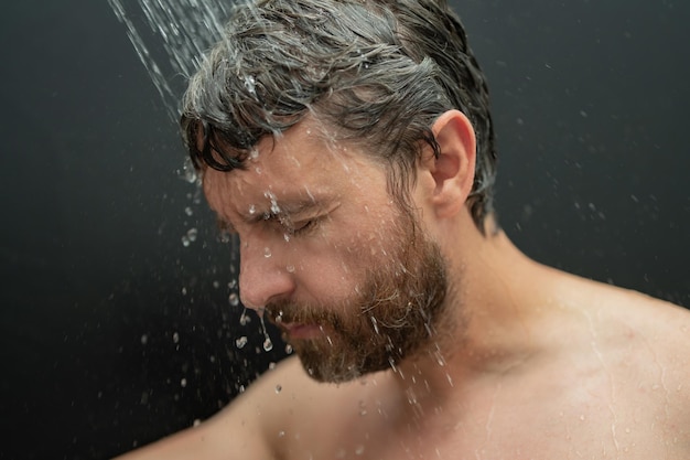 Homme se lavant les cheveux dans la salle de bain, homme se baignant, pomme de douche dans la baignoire, visage masculin dans la douche, homme prenant