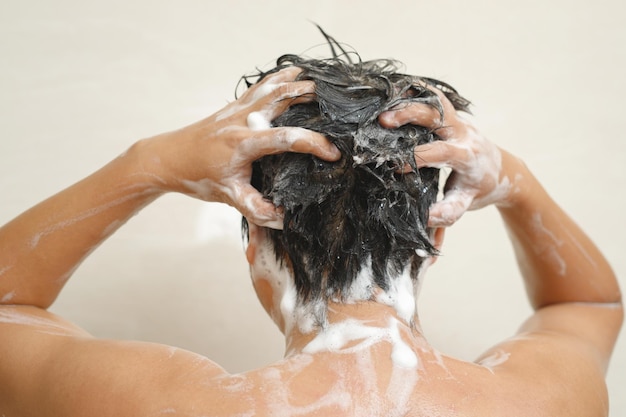 Un homme se lave les cheveux avec du shampoing