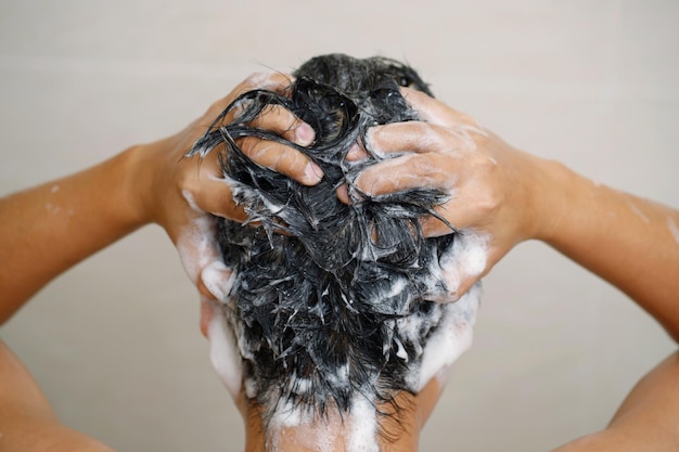 Un homme se lave les cheveux avec du shampoing