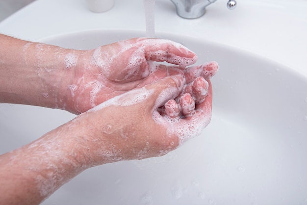 L'homme se lave les mains avec du savon avec de la mousse, photo conceptuelle sur le virus et l'hygiène