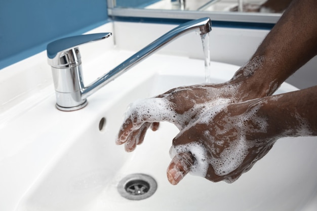 Photo l'homme se lave soigneusement les mains dans la salle de bain close up prévention de l'infection