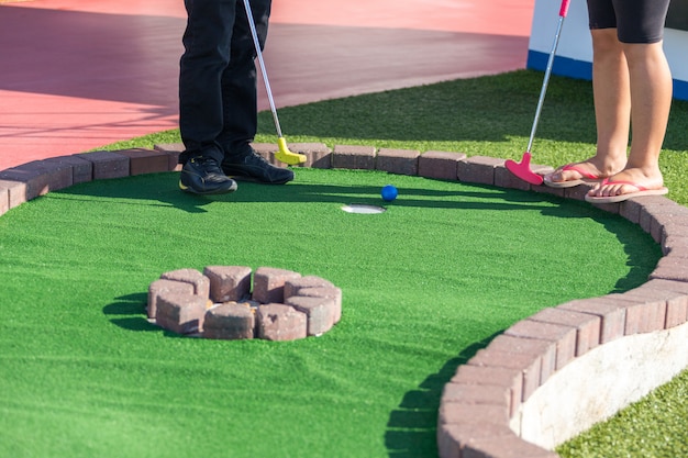 Un homme se prépare à frapper une balle pendant une partie de mini golf