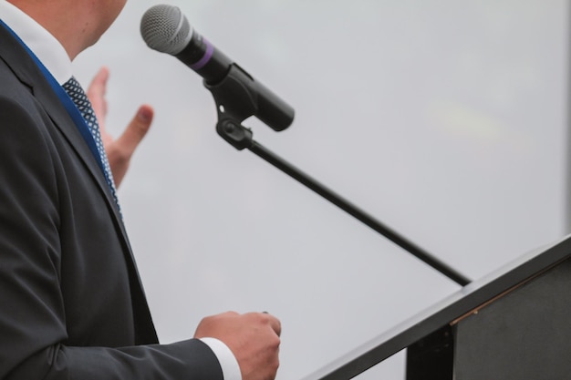 L'homme se produit lors d'une conférence - parle dans un microphone pour le public, prise de vue au téléobjectif