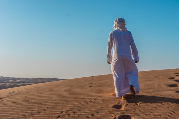 Un homme se promène dans le désert d'Oman.