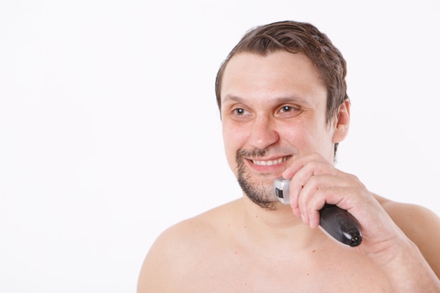 l'homme se rase le chaume. mec nettoie sa barbe avec un rasoir électrique. soins du matin dans la salle de bain.