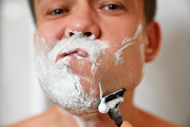 Un homme se rase le visage avec un rasoir de sûreté