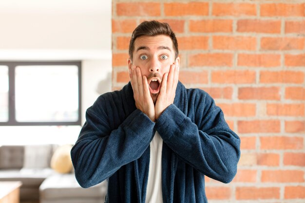 Homme se sentant choqué et effrayé, l'air terrifié avec la bouche ouverte et les mains sur les joues