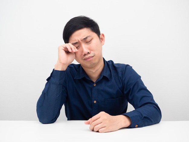 Homme se sentant triste et pleurant à la table fond blanc