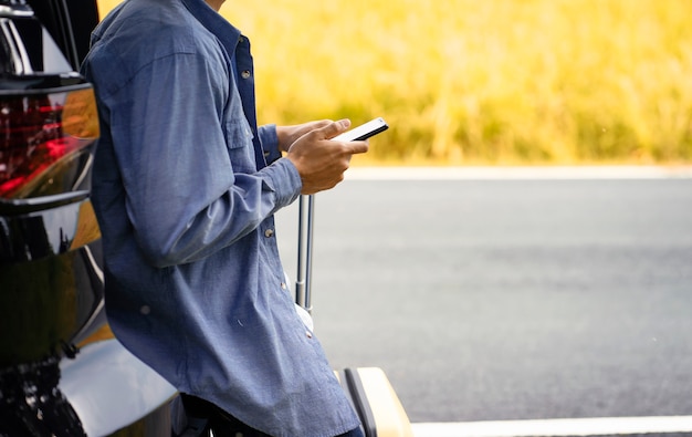 l'homme se tenait dans la voiture avec son téléphone portable et ses bagages