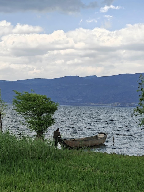 Un homme se tient à côté d'un bateau sur l'eau.