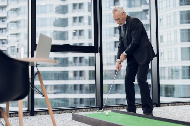 L&#39;homme se tient dans le fond de la fenêtre et détient le club de golf