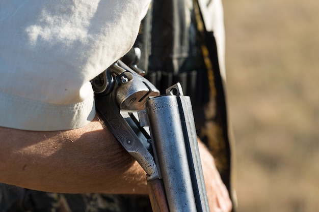 Un homme se tient debout avec des armes et des chiens de chasse traquant le gibier