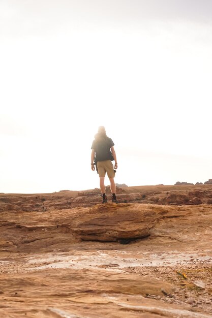 Photo un homme se tient debout sur un rocher au milieu d'un désert.