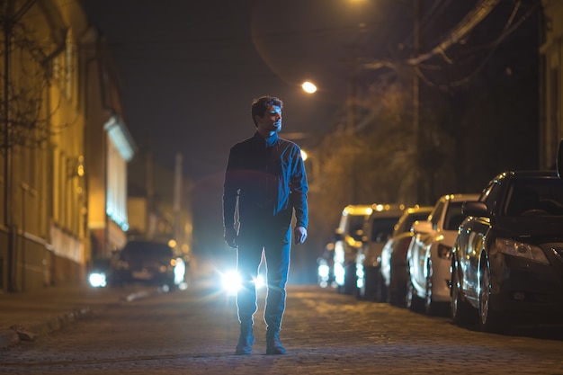 L'homme se tient à l'extérieur sur le fond d'un phare. Le soir la nuit