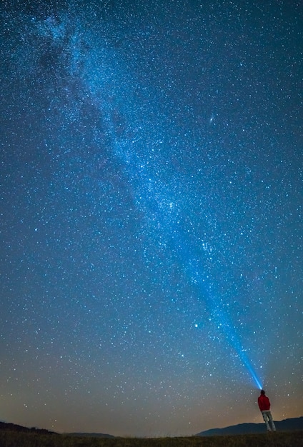 L'homme se tient sur le fond des étoiles dans le ciel. la nuit