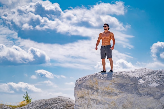 L'homme se tient sur un grand rocher contre le ciel