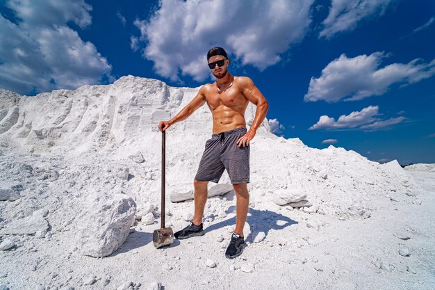 Un homme se tient sur une montagne blanche avec une pelle à la main.