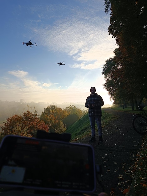 Un homme se tient sur un sentier avec un drone devant lui.