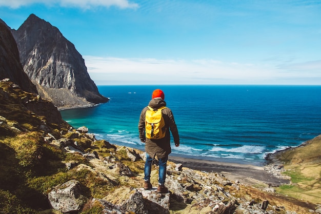 L'homme se tient seul au bord de la falaise, profitant d'une vue aérienne de l'aventure en sac à dos, des vacances en plein air