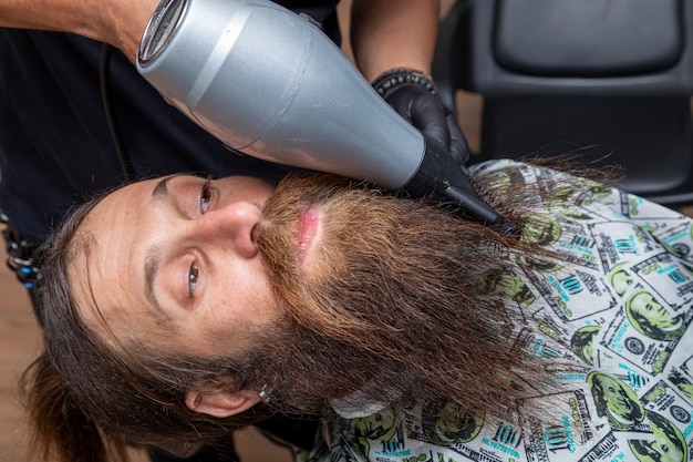 Homme séchant sa barbe chez le coiffeur.