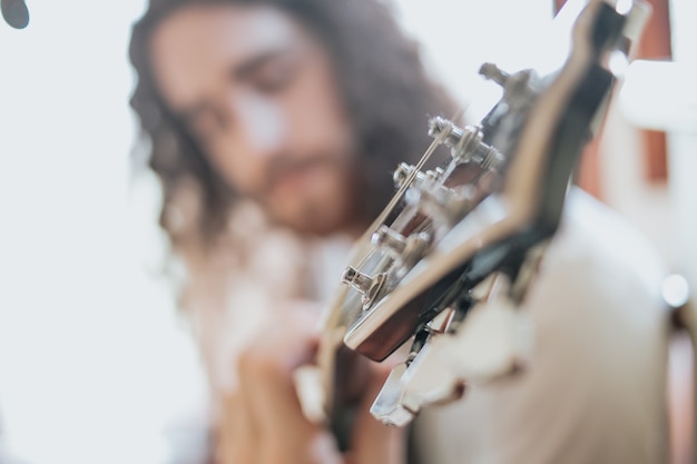 Homme séduisant aux cheveux longs jouant de la guitare acoustique à l'extérieur, hippie, détente, style de vie du parc, passe-temps, espace de copie