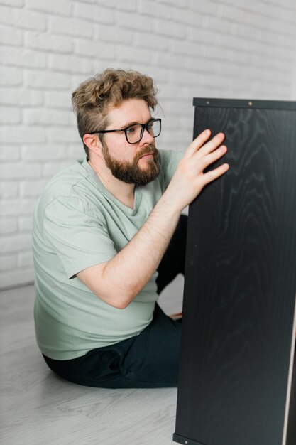 Un homme séduisant barbu assemble un artisan de meubles et un concept d'objets d'intérieur