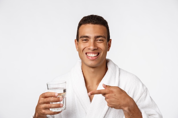 Un homme séduisant, boire un verre d'eau contre le blanc