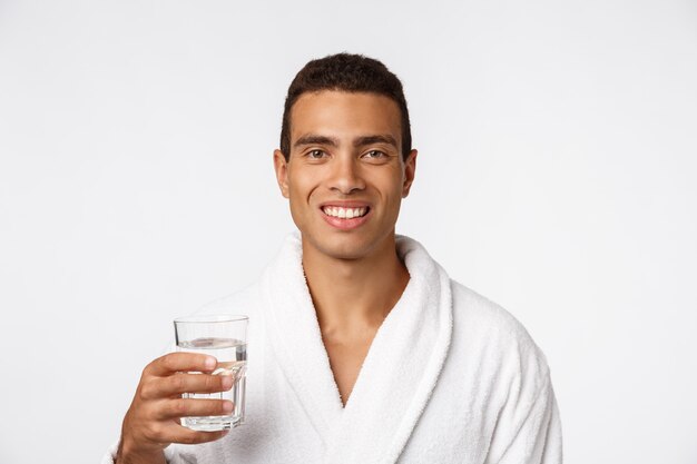 Un homme séduisant, boire un verre d'eau contre le blanc