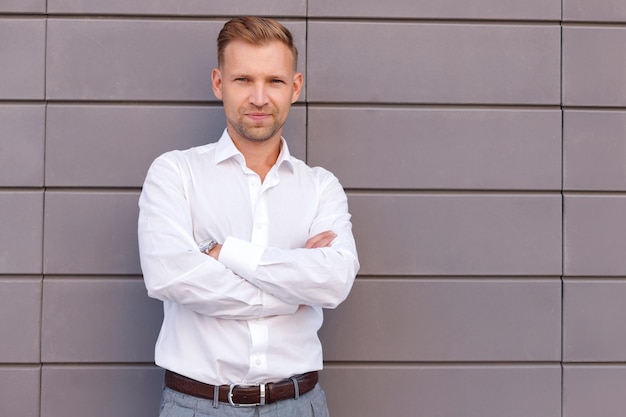 Homme séduisant en chemise blanche sur fond gris