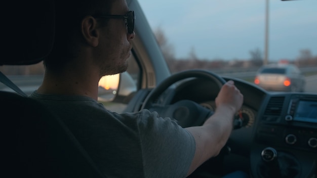 L'homme séduisant conduisant l'automobile le long de l'autoroute urbaine