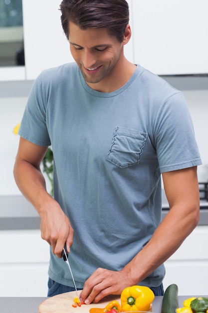 Homme séduisant coupe des légumes