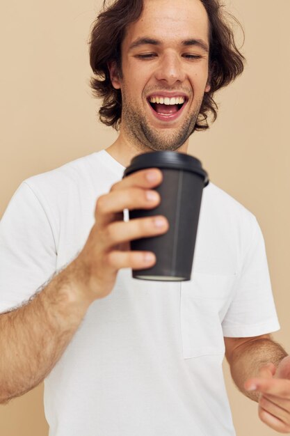 Homme séduisant dans un t-shirt blanc avec un verre noir à la main