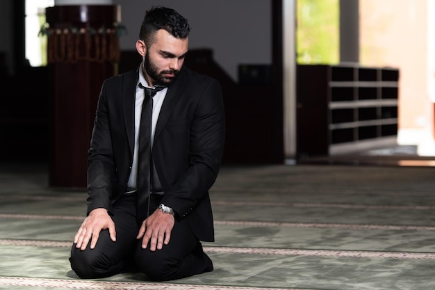 Homme séduisant faisant la prière traditionnelle à Dieu Allah dans la mosquée