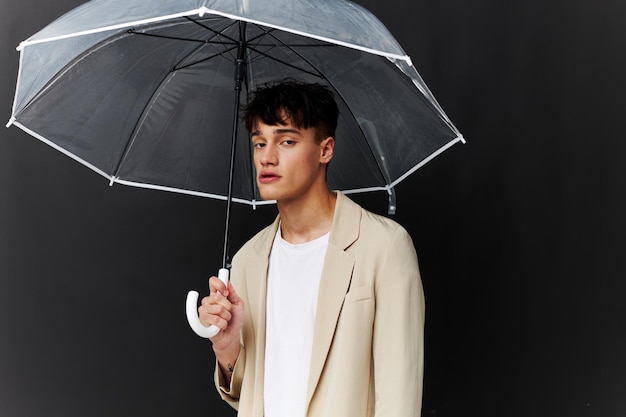 Homme séduisant avec parapluie transparent protection contre la pluie fond sombre