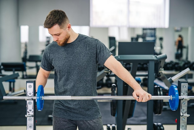 Homme séduisant de remise en forme s'entraînant dans la salle de gym Beau jeune entraîneur en bonne santé travaillant dans la salle de gym