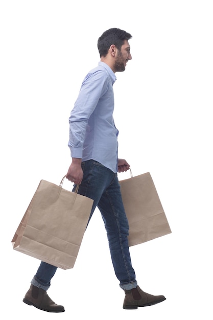 Homme séduisant avec des sacs à provisions marchant à la maison