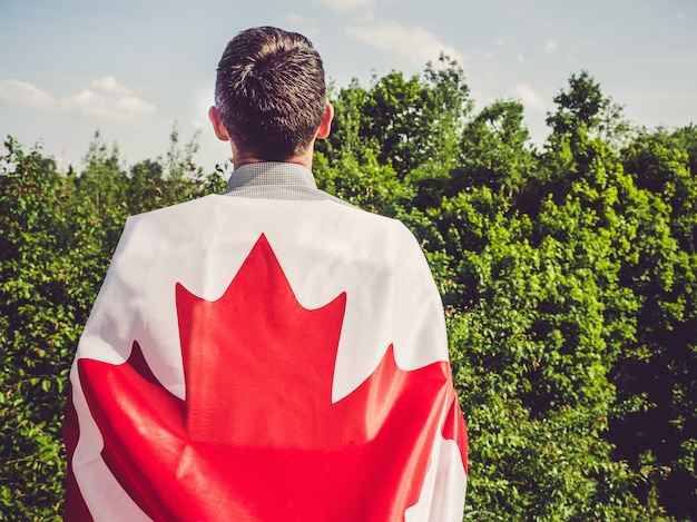 Homme séduisant tenant le drapeau canadien. fête nationale