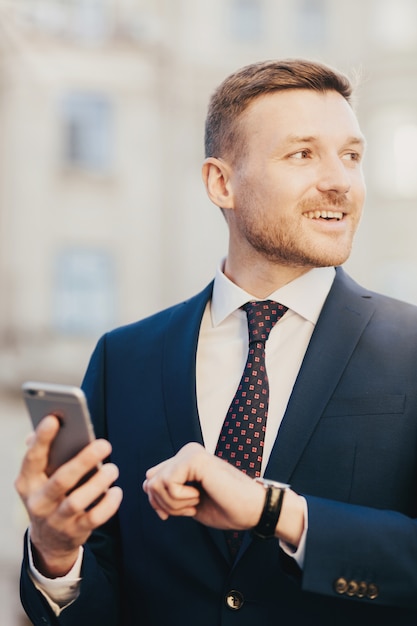 Un homme séduisant vient rencontrer le client, regarde la montre et tient un téléphone intelligent