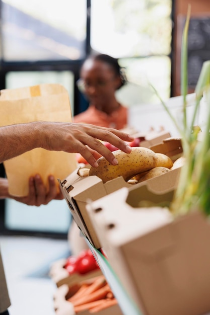 Photo un homme sélectionne des pommes de terre sur une étagère