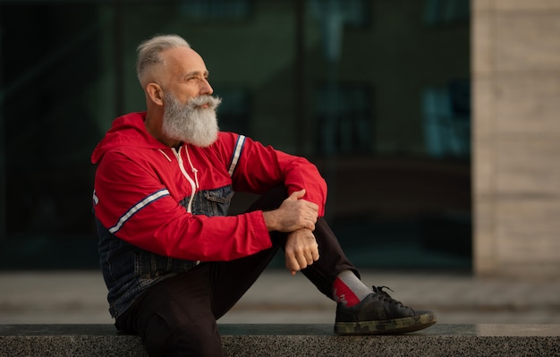 Homme senior actif marchant dans la ville. Portrait d'un homme senior avec une barbe en se tenant debout à l'extérieur.