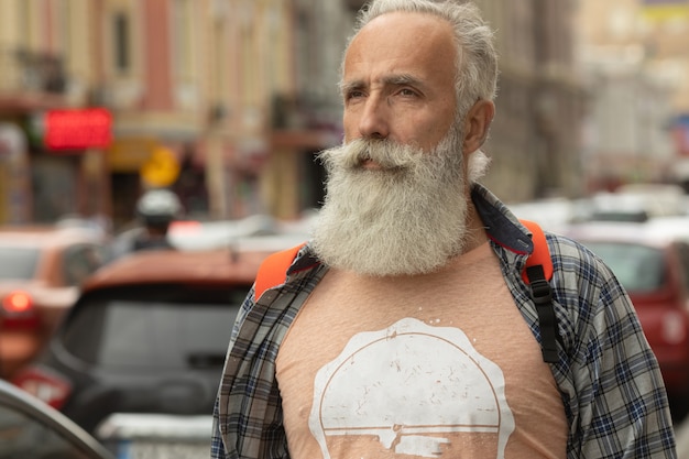 Homme senior actif marchant dans la ville. Portrait d'un homme senior avec une barbe en se tenant debout à l'extérieur.