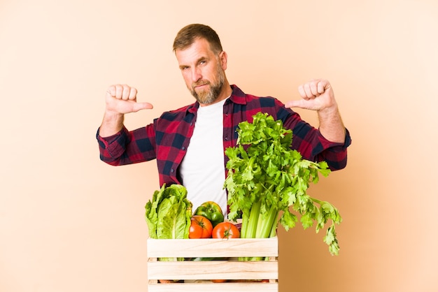 Homme senior agriculteur isolé sur fond beige se sent fier et confiant, exemple à suivre.