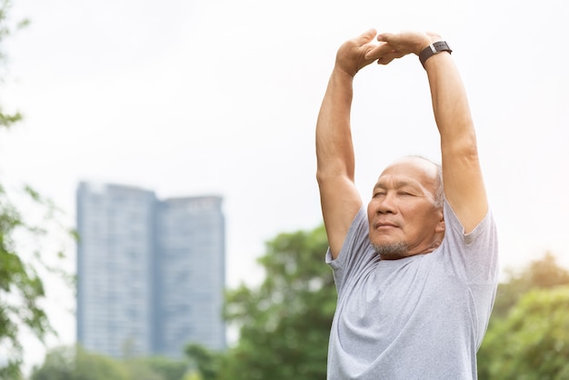 Homme senior asiatique étirant ses bras en l'air avant de faire de l'exercice.