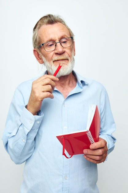 L'homme senior aux cheveux gris écrit des émotions dans un fond clair de cahier