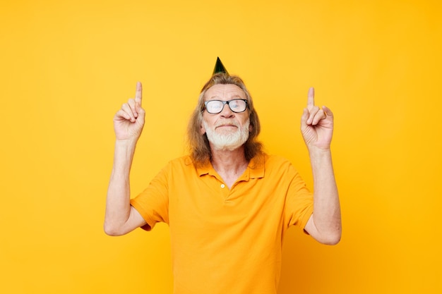 Homme senior aux cheveux gris portant des lunettes casquette verte sur la tête vacances émotions fond jaune