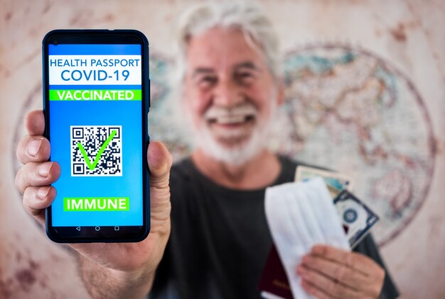 Un homme senior barbu heureux montre une application de passeport de santé numérique pour les personnes vaccinées contre le coronavirus